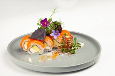 Avokadoyla süslenmiş suşi Philadelphia usulü. Tabakta otlar, klasik Japon suşisi. Geleneksel Japon yemeği ve maki. Lezzetli suşi parçaları. Restoran menüsü için. kopyalama alanı