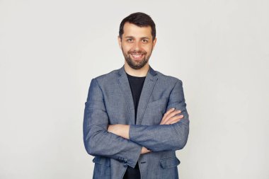 Mutlu bir yüzle gülümseyen sakallı genç bir adam, başparmağıyla reklam için bir yere bakıyor ve işaret ediyor, buraya bakın, izole bir arka planda..