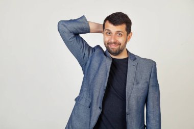 Gülümseyen genç bir işadamı, ceketli sakallı bir adam, bir sorun çıkacağından endişeleniyor, eli başında, krizden endişeli ve endişeli, gri arka plandaki bir adamın portresi.