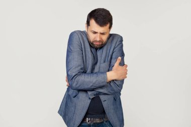 Ceketli, sakallı genç bir iş adamı. Yüzünde üzgün ve şok olmuş bir ifadeyle kış soğuğundan titriyor ve donuyor. Gri arka planda bir adamın portresi.