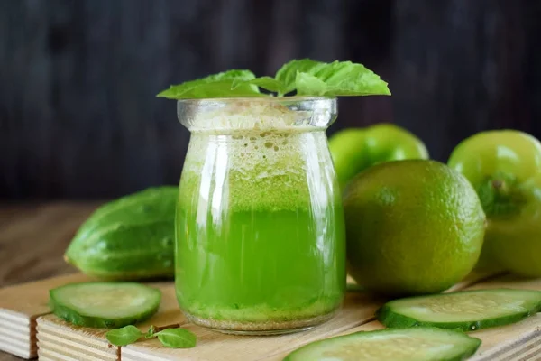 Green cocktail in a glass jar sprinkled with brans decorated with basil against the wooden background