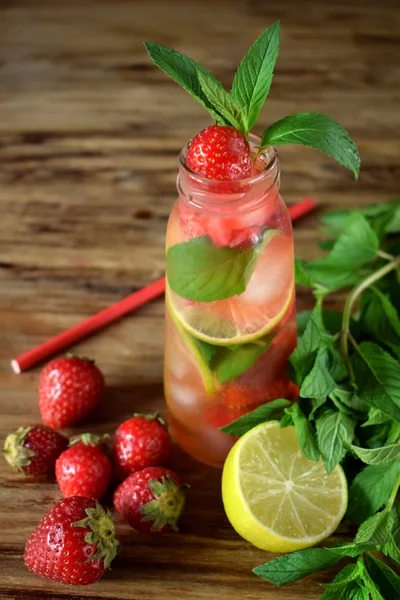 Lemonade with strawberry, lime, ice cubes and mint in a glass bottle