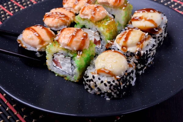 Set of baked sushi rolls on a black plate