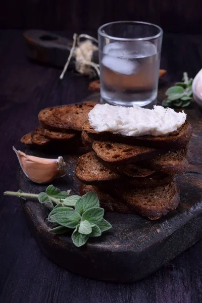 Rye bread toasts, lard paste and a misted glass of vodka on a black board. Ukrainian cuisine appetizer — Stock Image Rye Bread Toasts Lard Paste Misted Glass Vodka Black Board Royalty Free Stock Images