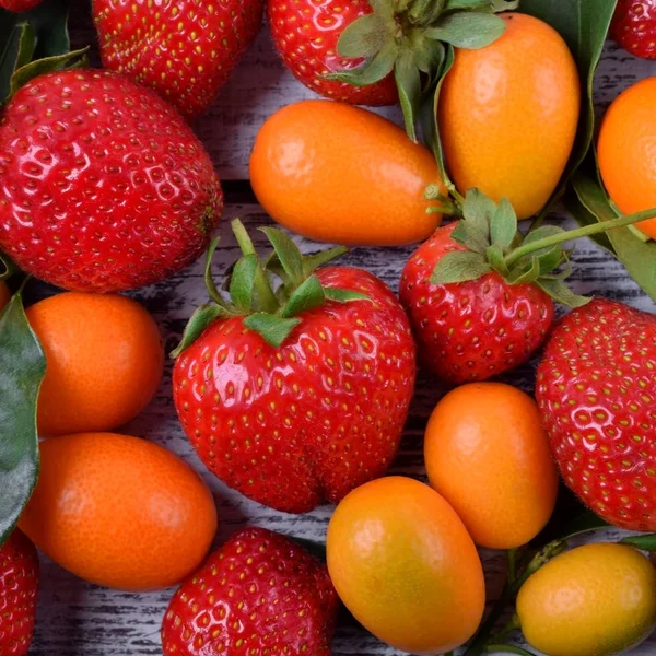 Strawberries and kumquats. Mix of fruit and berries. Summer background