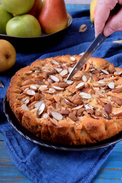 Pie with pears, apples and almonds on a black ceramic plate
