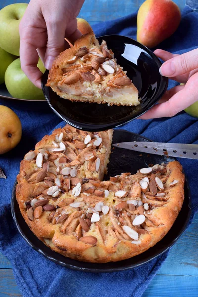 Pie with pears, apples and almonds on a black plate