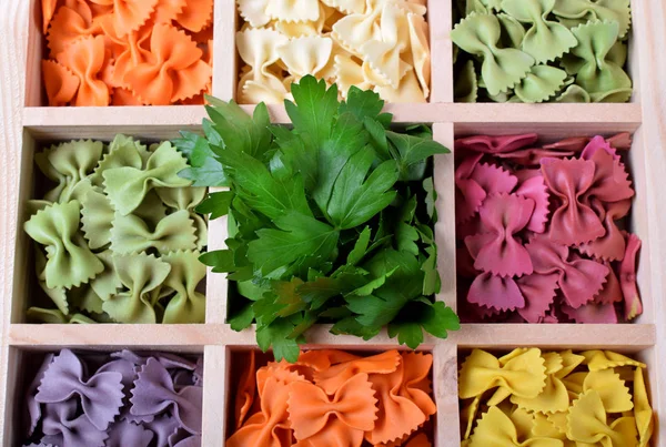 Multicolored pasta farfalle in wooden box