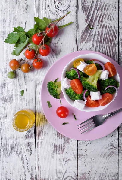 Light salad with broccoli, cherry tomatoes and feta cheese in a white ceramic bowl