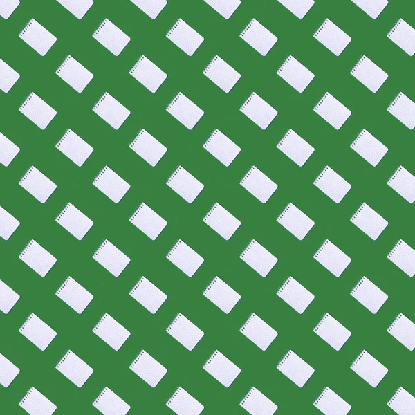 Seamless pattern with notebooks against the green background