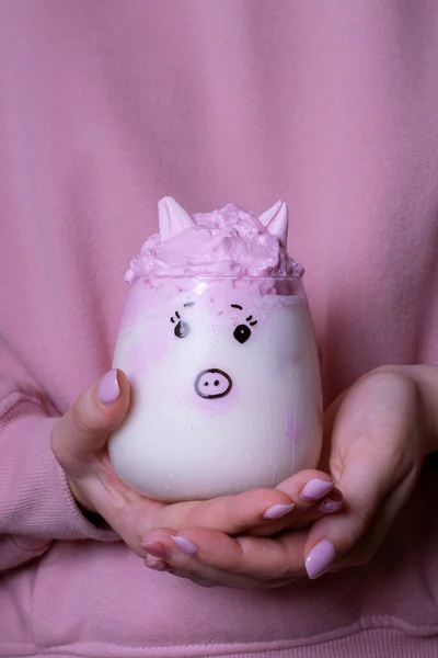 Piggy whipped milk in woman hands against the pink hoodie