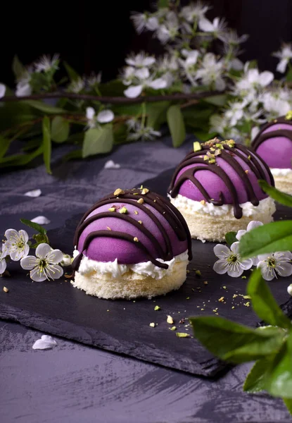 Bilberry mousse cakes semisphere-shaped and topped with chocolate and pistachio nuts