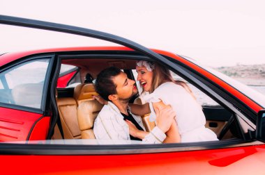 16 Ekim 2016, Maghtab, Malta. Beyaz elbise ve kırmızı Ferrari, ön koltukta oturan adam genç kız seaside