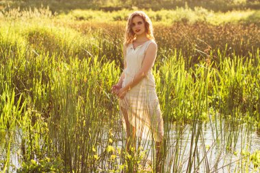 Güzel kız nehir ve sıkmak beyaz elbise ortasında ayakta