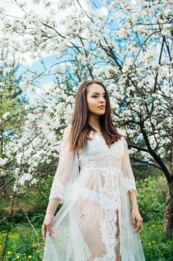 Çiçeği elma bahçesinde beyaz elbiseli Genç kız elbise elle tutarak portresi