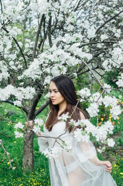 Çiçeği elma bahçesinde beyaz elbiseli Genç kız elbise elle tutarak portresi
