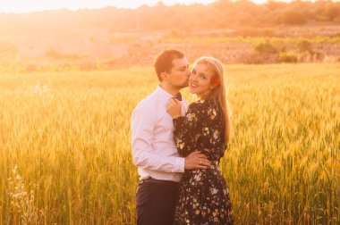 Kucaklayan ve buğday alanında dusk, kırsal Malta öpüşme kadın ve erkek