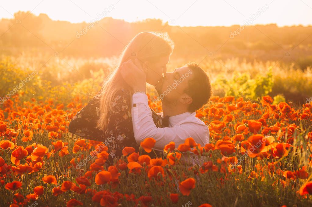 Man and woman embracing and kissing in poppy field on the dusk,  countryside Malta