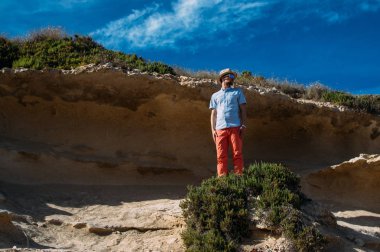 Güneş gözlüğü ve kırmızı pantolon tepelerde, Malta kalan adam