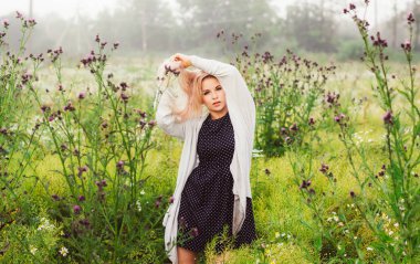 Genç kız saç, ilk plan thistle holding eller papatya alanında dans portresi