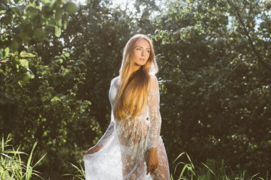 Genç güzel kız beyaz dantel elbise elma bahçesinde poz