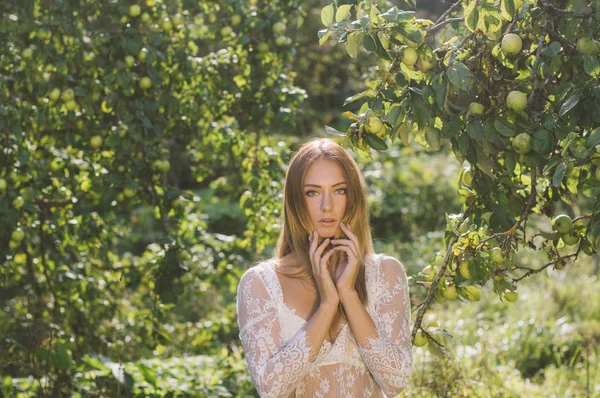 年轻美丽的女孩的肖像在白色蕾丝礼服在苹果花园 手靠近脸 — 图库照片