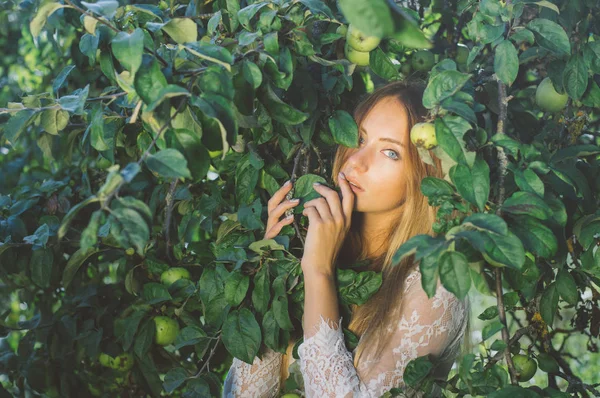 年轻美丽的女孩的肖像在白色蕾丝礼服在苹果庭院 在树冠 手指近嘴 — 图库照片