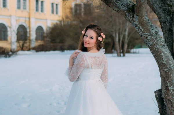 Bride with roses in hair turned back, winter on background