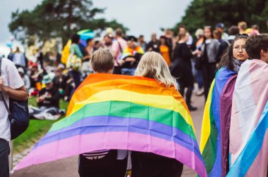 Helsinki, Finlandiya - 30 Haziran 2018: Gökkuşağı bayrağı Helsinki üzerinde Kaivopuisto bahçesinde iki kızla Festivali gurur duyuyoruz