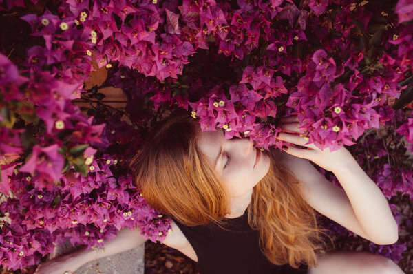 Portrait of girl with closed eyes among purple bougainvillaea, springtime