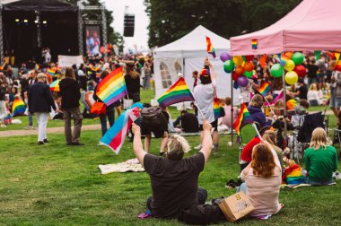 Çift gökkuşağı bayrakları sallanan ve çim üzerinde oturan