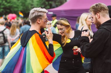 İnsanlar Helsinki Pride'da piknikte sigara içip bira içiyor.