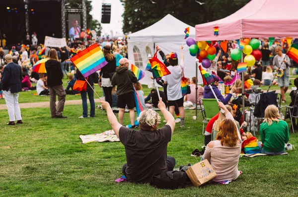 Par svängande Rainbow flaggor och sitter på gräset — Stockfoto