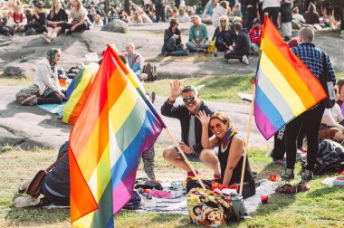 Helsinki Pride festivalinde piknikte büyük bayraklı insanlar 