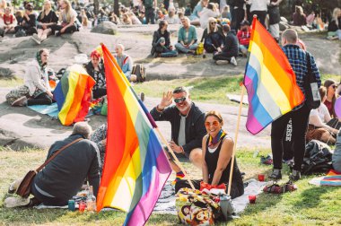Helsinki Pride festivalinde piknikte büyük bayraklı insanlar 
