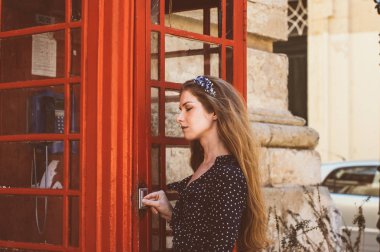 Telefon kulübesinin yanında gözleri kapalı genç bir kadın. 