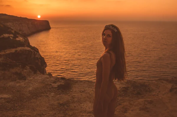 Jonge vrouw verblijf op de berg op de oever in lichaam in zonsondergang — Stockfoto
