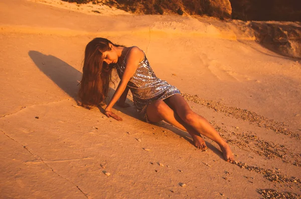 Jonge vrouw zitten op zand steen in kreupele jurk — Stockfoto