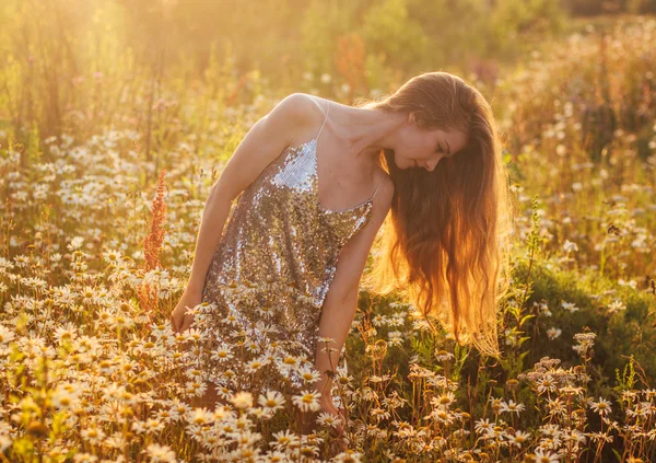 Mädchen im blinkenden Kleid bleibt inmitten eines Kamillenfeldes — Stockfoto