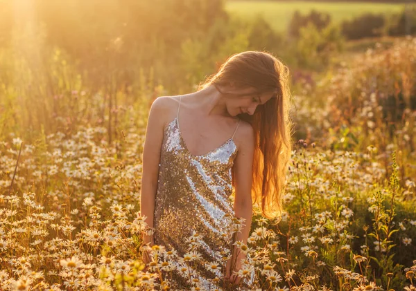 Улыбающаяся девушка в мигающем платье, остающаяся среди ромашки — стоковое фото