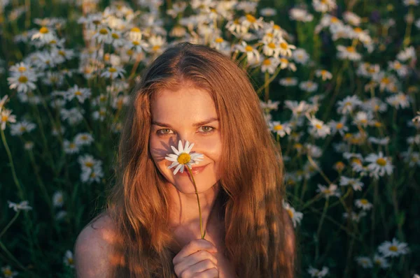Portrait of pretty smiling blond woman sitting in chamomile fiel — Stock Photo, Image