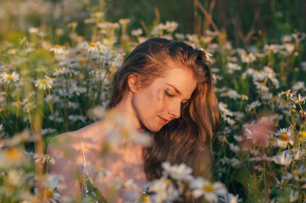 Portrait of pretty blond woman sitting in chamomile field — Stock Photo, Image