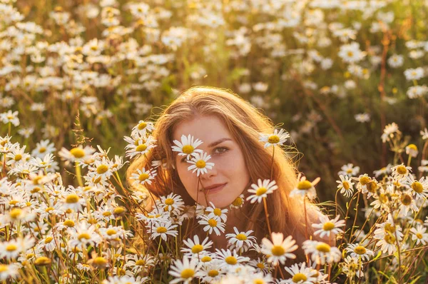 Portret van een mooie blonde vrouw zittend in kamille veld — Stockfoto