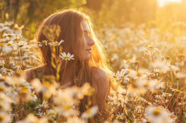 Retrato lateral de una hermosa mujer rubia sentada en el campo de manzanilla — Foto de Stock