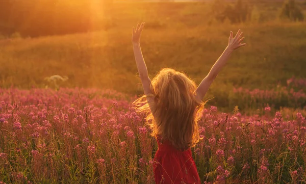 Bailando y saltando chica con las manos arriba en vestido rojo entre bloomi — Foto de Stock