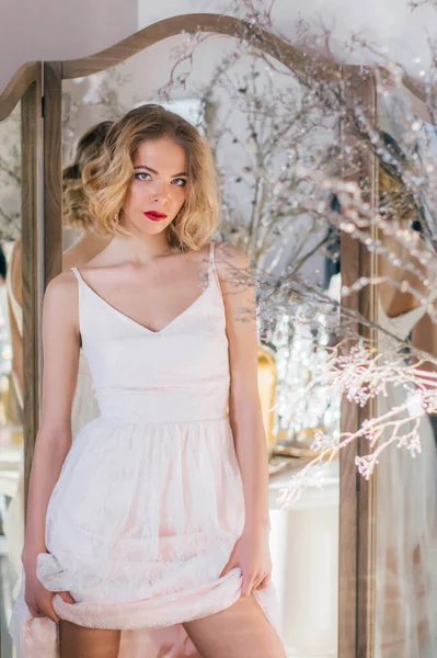 Kaliteli makyajlı ve saç stili güzel sarışın kız aynanın yanında duruyor.