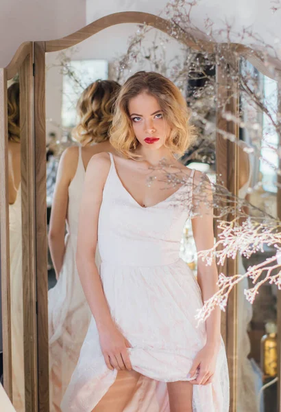 Kaliteli makyajlı ve saç stili güzel sarışın kız aynanın yanında duruyor.