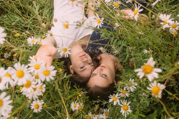 二人の女の子でダークブルーとホワイトドレスで晴れた日に横たわっでカモミールフィールド上自然 — ストック写真