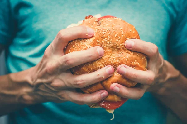 Juisy 木製の背景に男性の手で牛肉のハンバーガー。食品のコンセプト. — ストック写真