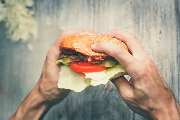 Homem come um sanduíche grande com carne e wegetables — Fotografia de Stock